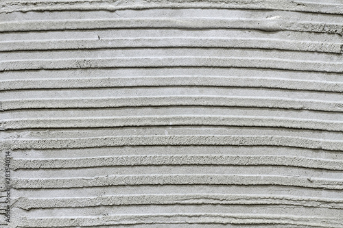 Rough grooved gray textured cement wall with pattern prepared for laying tile. Closeup