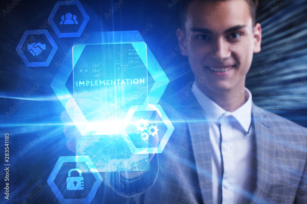The concept of business, technology, the Internet and the network. A young entrepreneur working on a virtual screen of the future and sees the inscription: Implementation The concept of business, technology, the Internet and the network. A young entrepreneur working on a virtual screen of the future and sees the inscription: Implementation