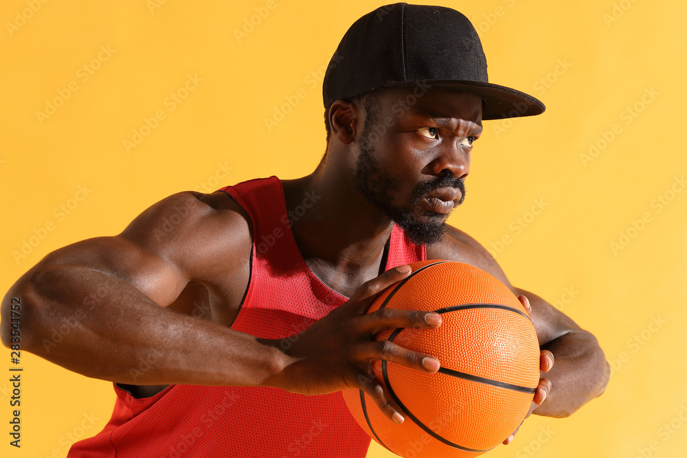 Modish gear temperatur Man in red shirt and black cap hold basketball ball in hands in front of  him. Studio, yellow background Stock-foto | Adobe Stock