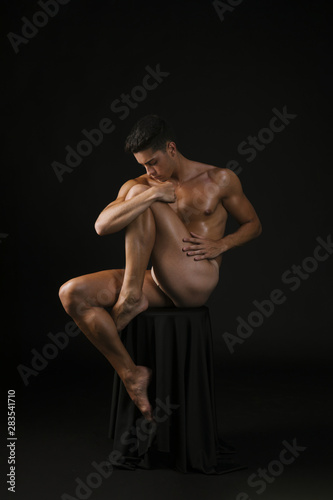 Naked guy embracing knee