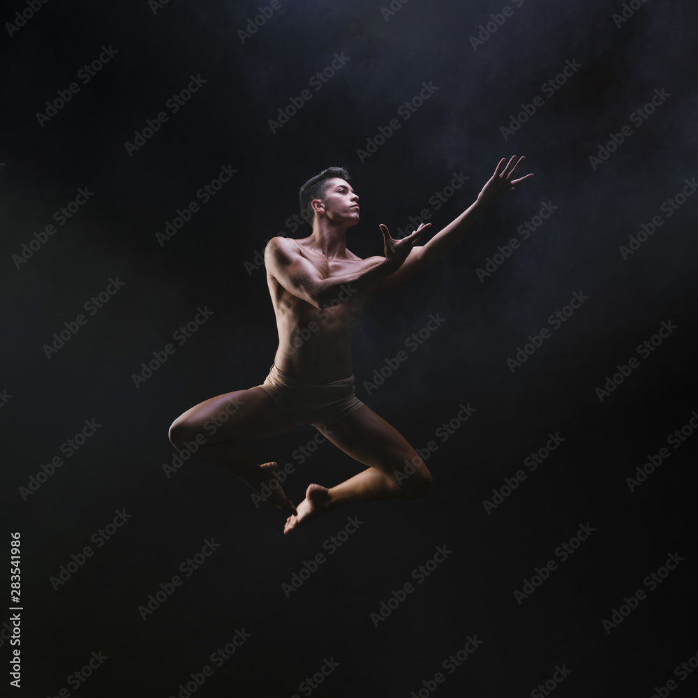 Naked muscled male jumping and raising hands