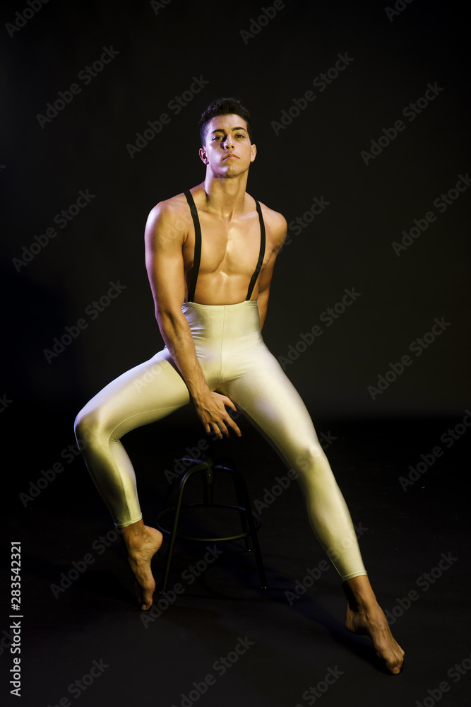 Graceful male ballet dancer resting in spotlight