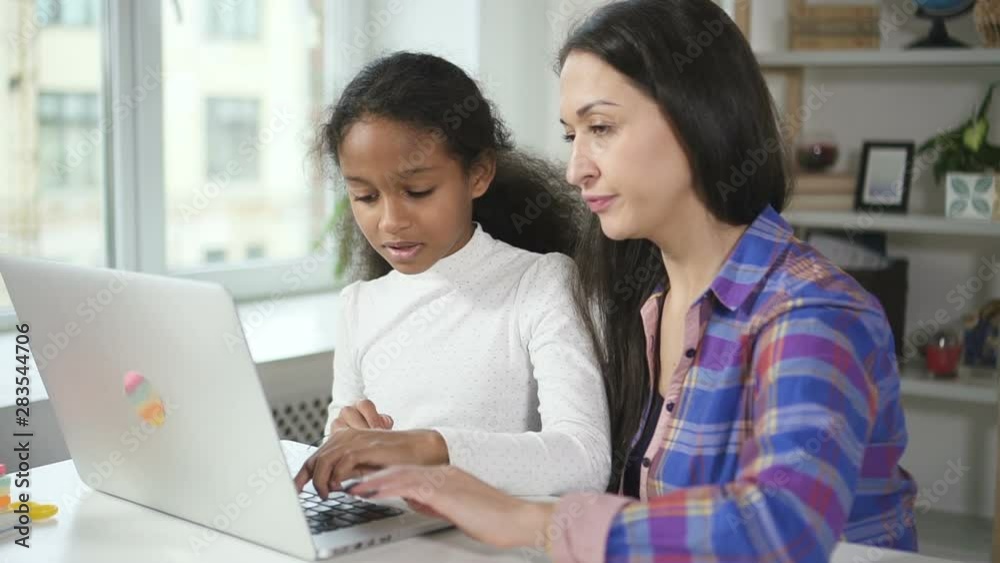 Young afro girl is agree with caucasian tutor in learning online by using new modern technology laptop. Education at home with computer instead book, notebook and looking information with internet Young afro girl is agree with caucasian tutor in learning online by using new modern technology laptop. Education at home with computer instead book, notebook and looking information with internet