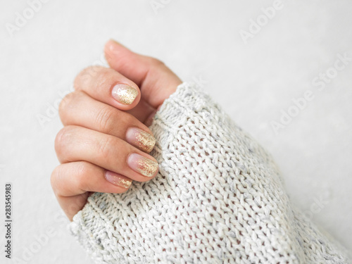 Manicure salon concept. Beautiful women hands with golden nail manicure on a white background. Gold nail polish. Closeup