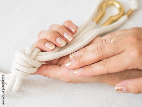 Manicure salon concept. Beautiful women hands with golden nail manicure on a white background. Gold nail polish. Closeup