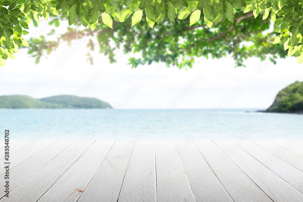 Fototapeta premium Old empty wooden table and palm leaves with party on beach blurred background in the daytime.