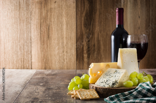 Assortment of cheeses and wine on wooden table. Copyspace