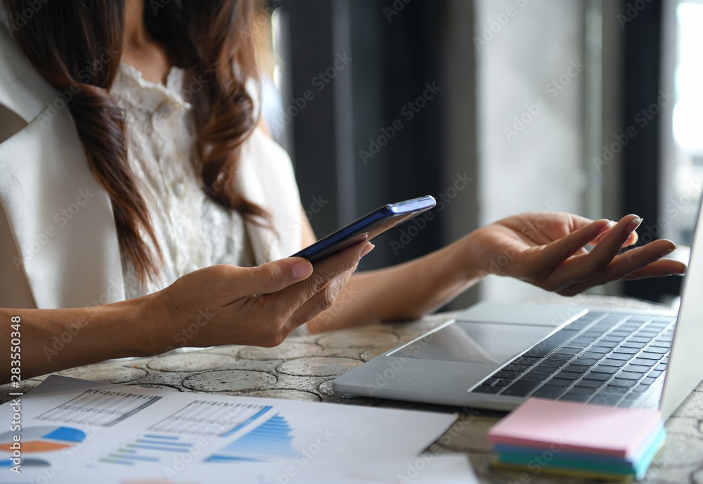 Executive women are using smartphone and laptop to summarize earnings. Executive women are using smartphone and laptop to summarize earnings.
