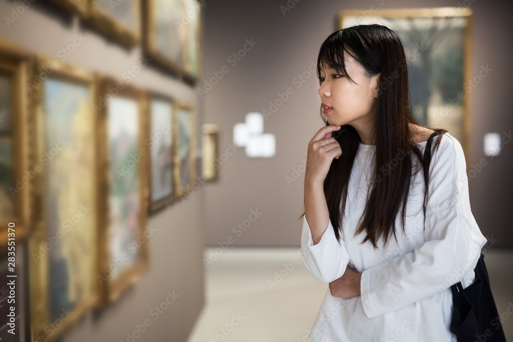 Chinese woman near picture collection in museum