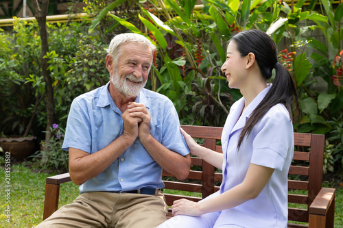 Smiling happy elderly man with nurse in garden at nursing home