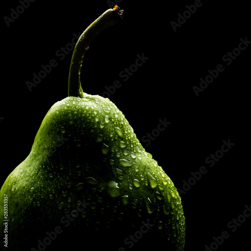 Beautiful green pear isolated on black background with lots of water droplets