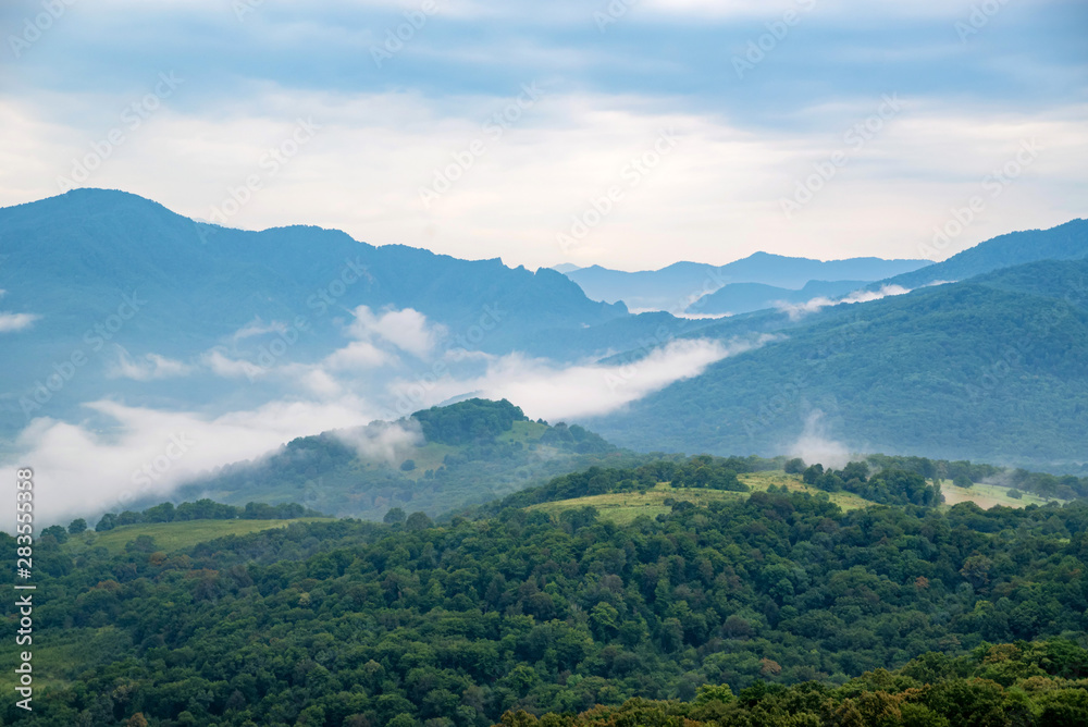Scenic view of foggy mountains. Clouds and green mountain forest view Scenic view of foggy mountains. Clouds and green mountain forest view