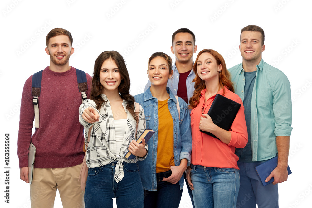 Obraz premium education, high school and people concept - group of smiling students with books and bags pointing at you over white background