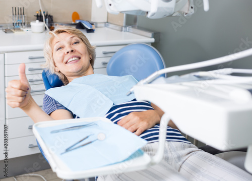 Satisfied woman visiting dentist giving thumbs up