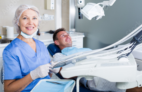 Dentist in dental clinic with patient behind