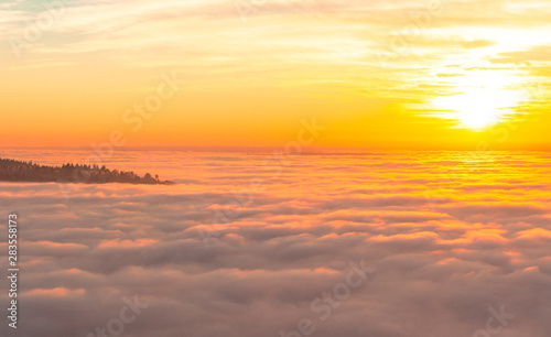 Sunset at Seattle during a cold autumn day with the Elliott Bay covered by clouds and a completely orange sky