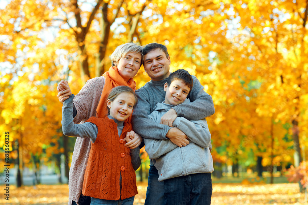 Happy family posing, playing and having fun in autumn city park. Children and parents together having a nice day. Bright sunlight and yellow leaves on trees, fall season. Happy family posing, playing and having fun in autumn city park. Children and parents together having a nice day. Bright sunlight and yellow leaves on trees, fall season.