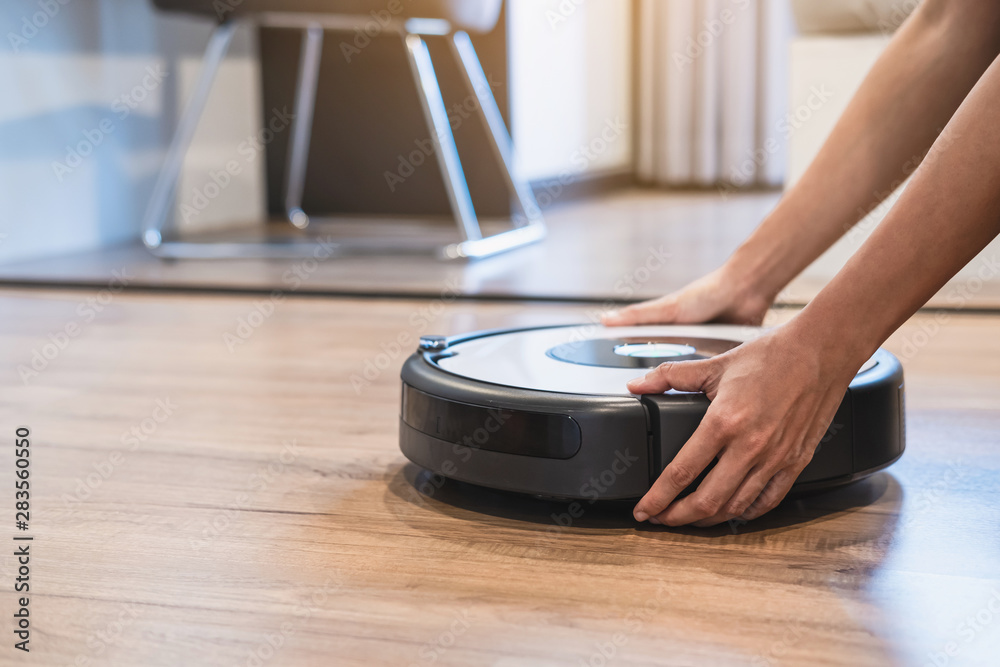 Fototapeta premium Robotic vacuum cleaner working on laminate wooden floor