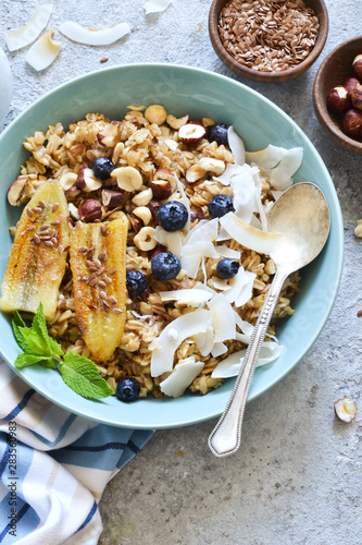 Oatmeal with caramel, banana, blueberries and coconut chips on a concrete background.
