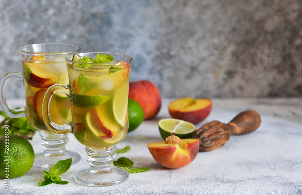Cold summer drink with peach, lime and mint on a concrete background. Cold summer drink with peach, lime and mint on a concrete background.