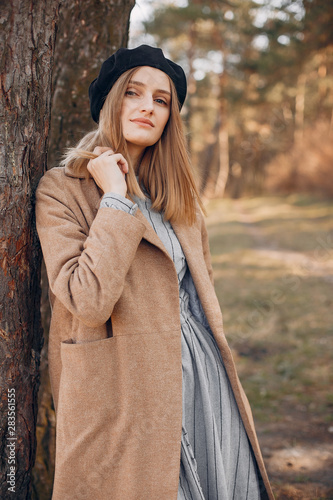 Beautiful girl in a park. Stylish girl in a brown coat
