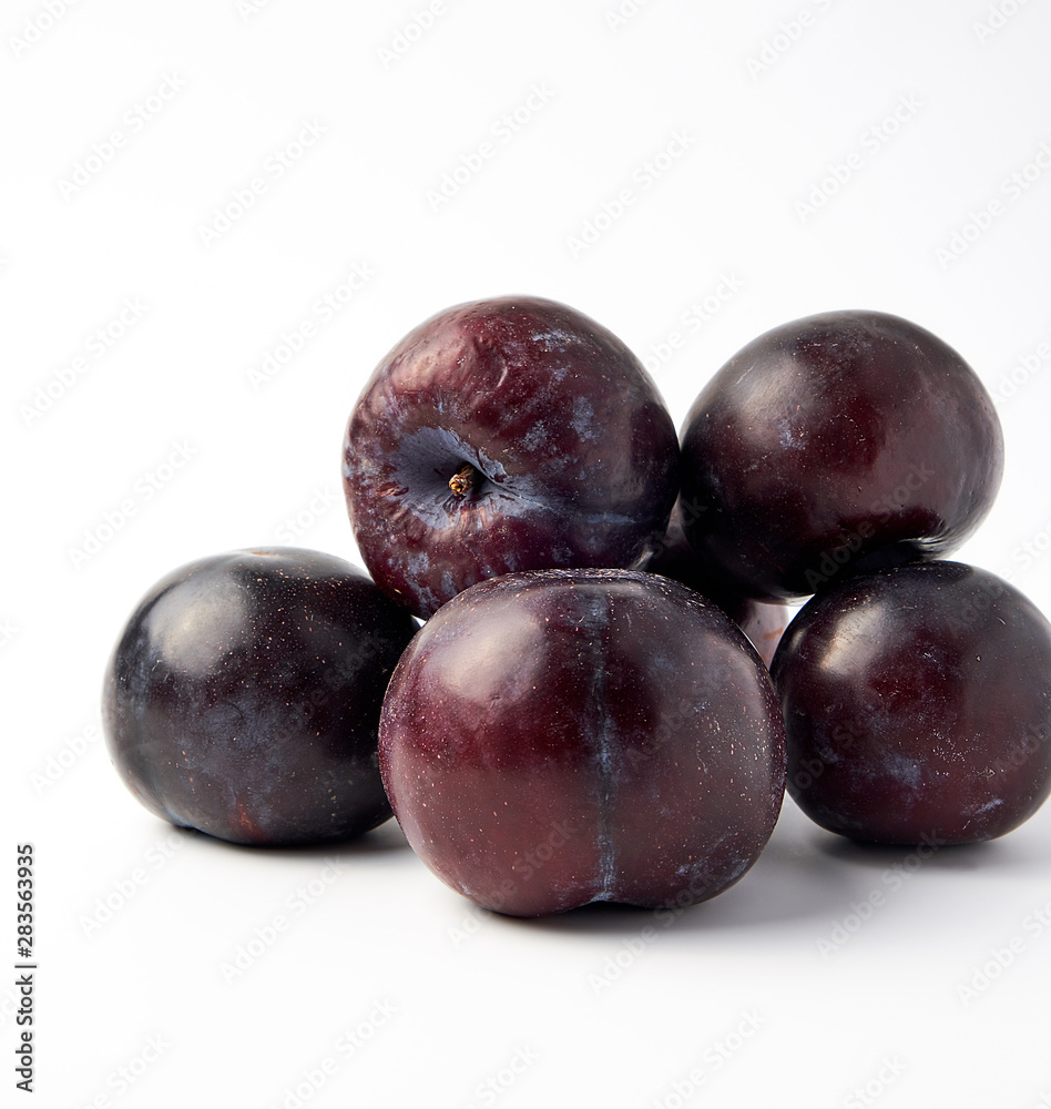 bunch of ripe fresh blue round plums on a white background