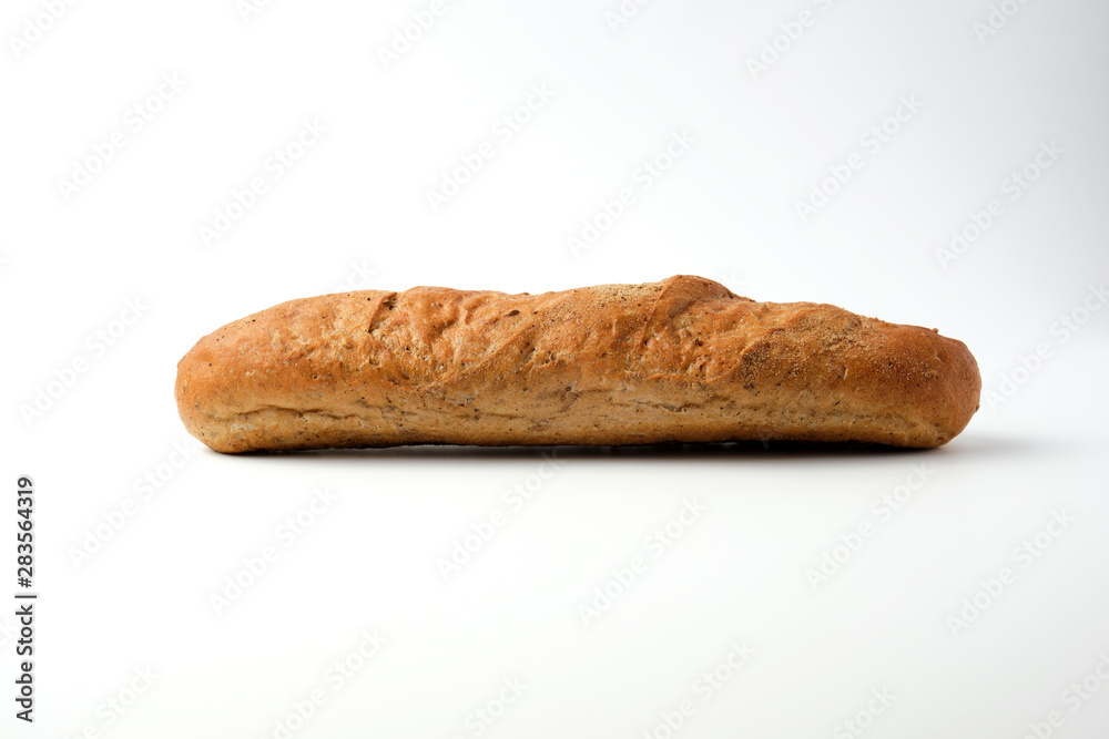 side view of a baked rye flour baguette on a white