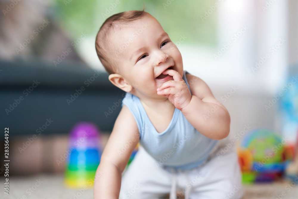 Cute smiling baby boy crawling on floor in living room Cute smiling baby boy crawling on floor in living room