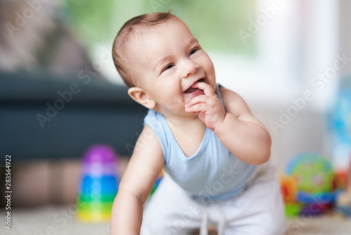 Cute smiling baby boy crawling on floor in living room