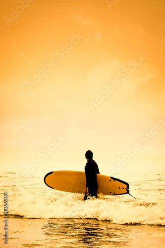 Surfer on the beach and sandy sea shore with the beautiful golden sunset view.