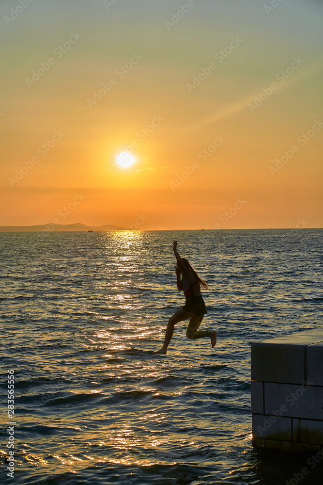 Jumping to the sea silhouette in the Sunset of Zadar. Croatia. Europe