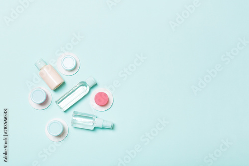 Top view of means for face care: bottles and jars of tonic, micellar cleansing water, cream, cotton pads on blue background. Bodycare concept with empty cpace for your ideas