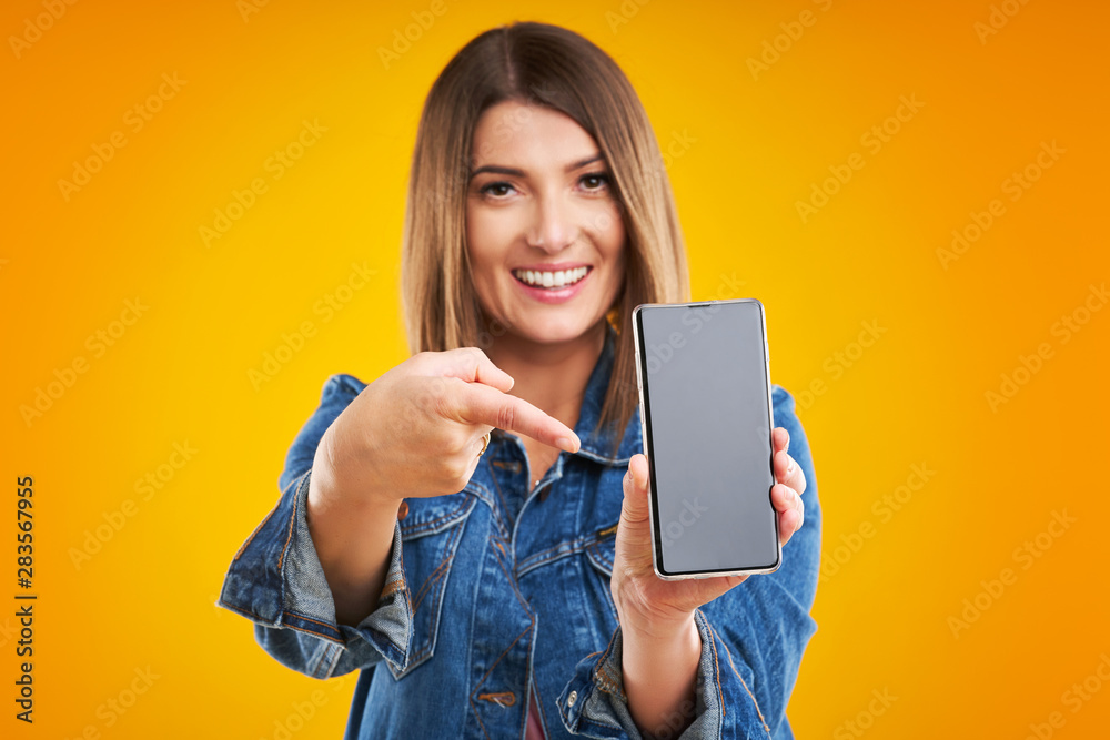 Close up of woman in denim jacket with smartphone over yellow background Close up of woman in denim jacket with smartphone over yellow background