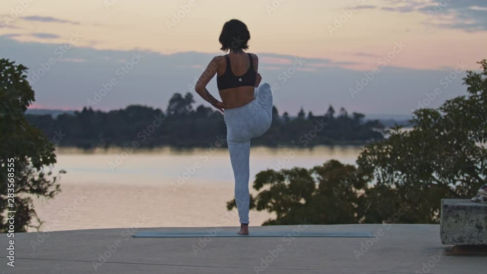 Young hispanic woman holds a difficult standing yoga pose on one leg.