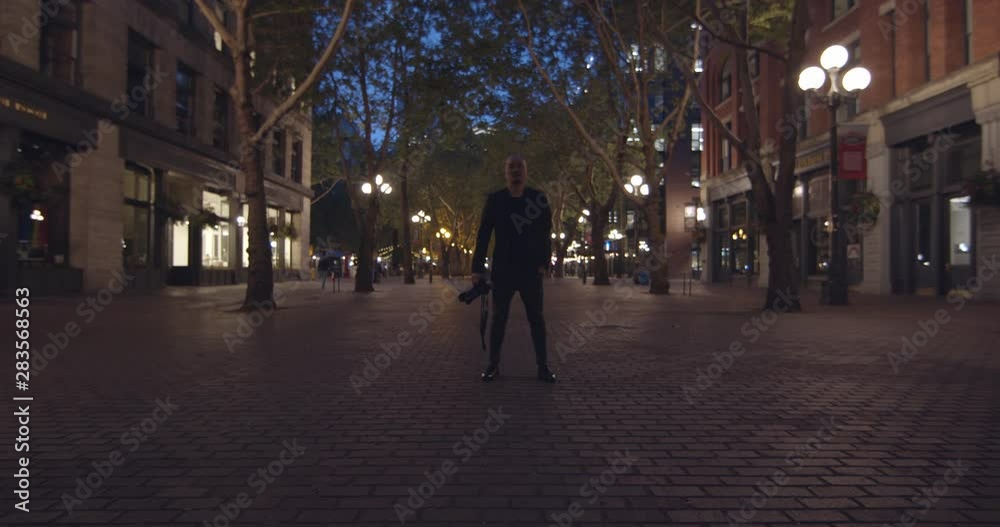 Slow Motion Slide Towards Photographer Man Standing in the Middle of the Square Holding a Camera