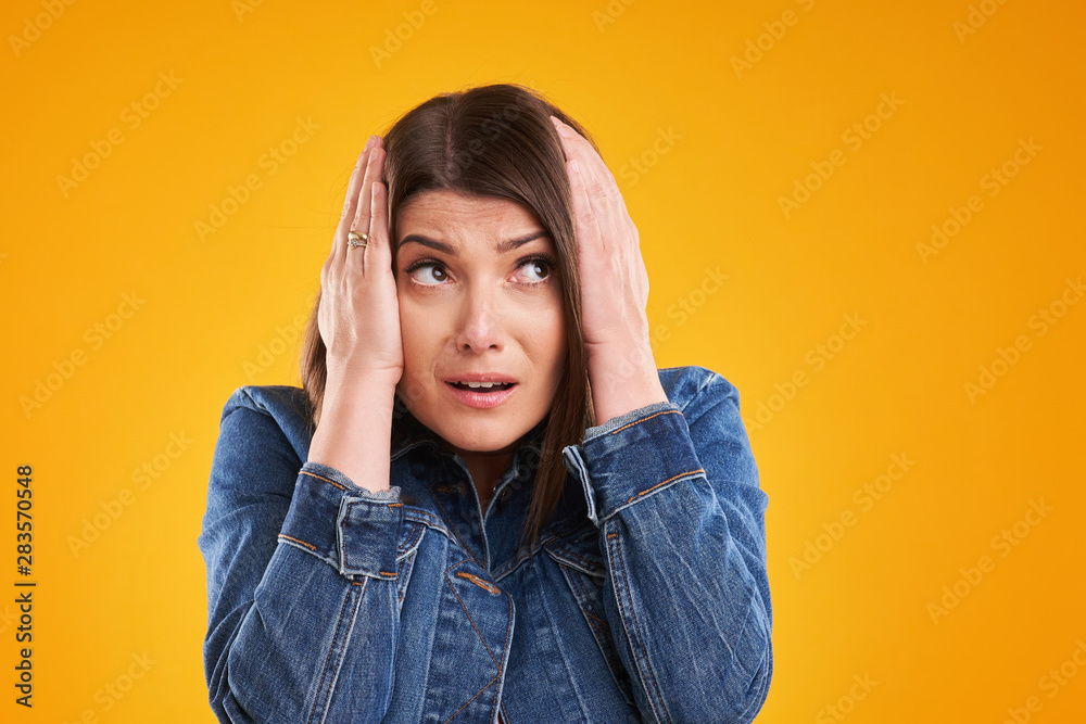 Unhappy woman in denim jacket over yellow background Unhappy woman in denim jacket over yellow background