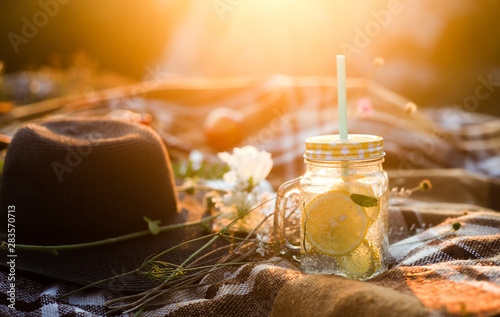 Summer picnic outdoors, summer drink jar with lemonade, plaid in the warm sunlight