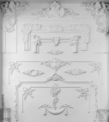 Decorative item made of white plaster on ceiling and wall. Beautiful ornament and relief stucco interior