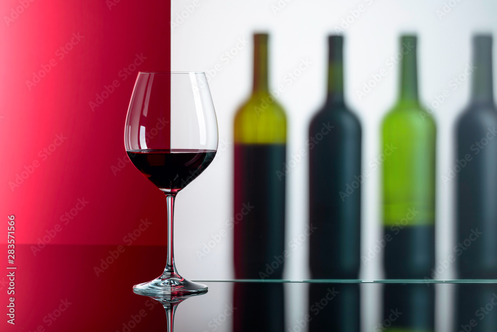 Bottles and glass of red wine on a black reflective background.