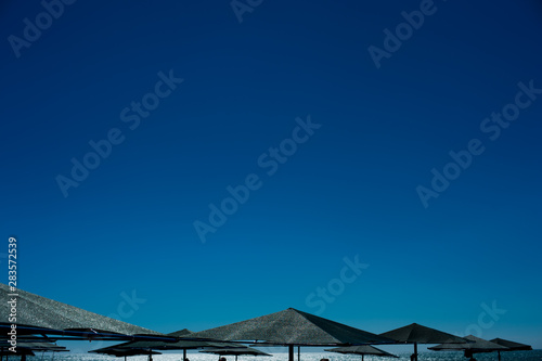 Relaxing beach background with umbrellas, sea and blue clear sky © Iaroslav