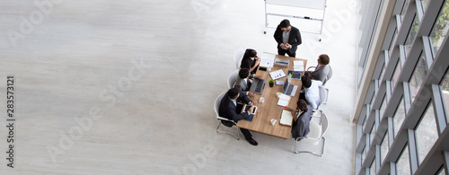 Top view of group of multiethnic busy people working in an office, Aerial view with businessman and businesswoman sitting around a conference table with blank copy space, Business meeting concept photo