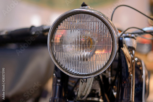 Round soviet headlight of retro motorcycle closeup beige background