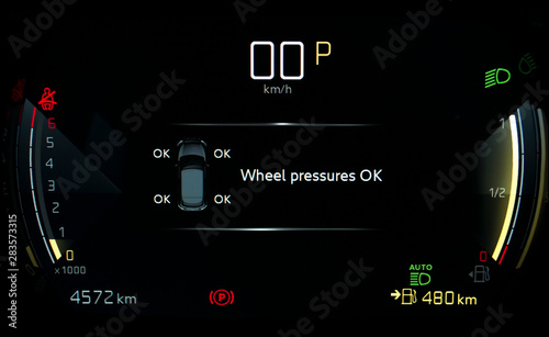 TPMS (Tyre Pressure Monitoring System) monitoring display on car dashboard panel. Checking tires pressures. Car instrument panel with speedometer, tachometer, odometer, fuel gauge, seatbelt reminder.