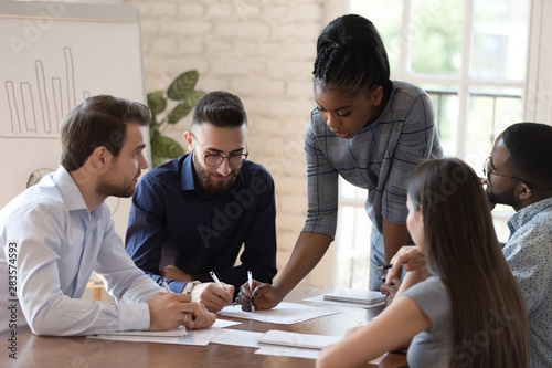 Serious african woman boss explain paperwork at group meeting