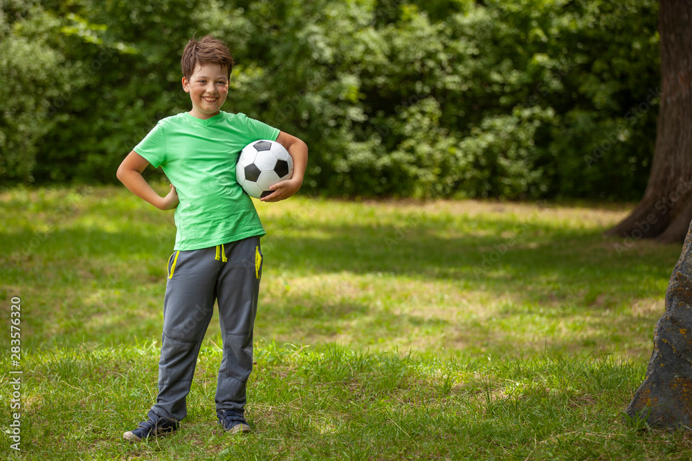 child play soccer player. Boy with ball on green grass