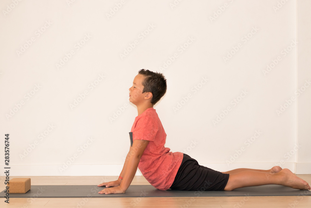 Niño joven realizando estiramientos para una clase de yoga Niño joven realizando estiramientos para una clase de yoga