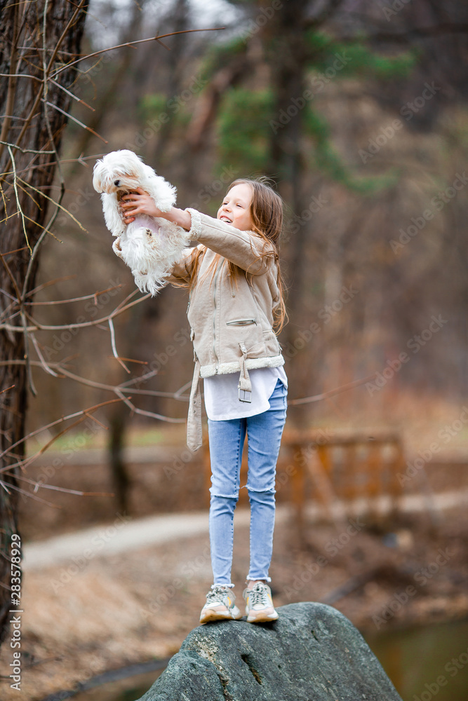Obraz premium Little girl with a white puppy. A puppy in the hands of a girl