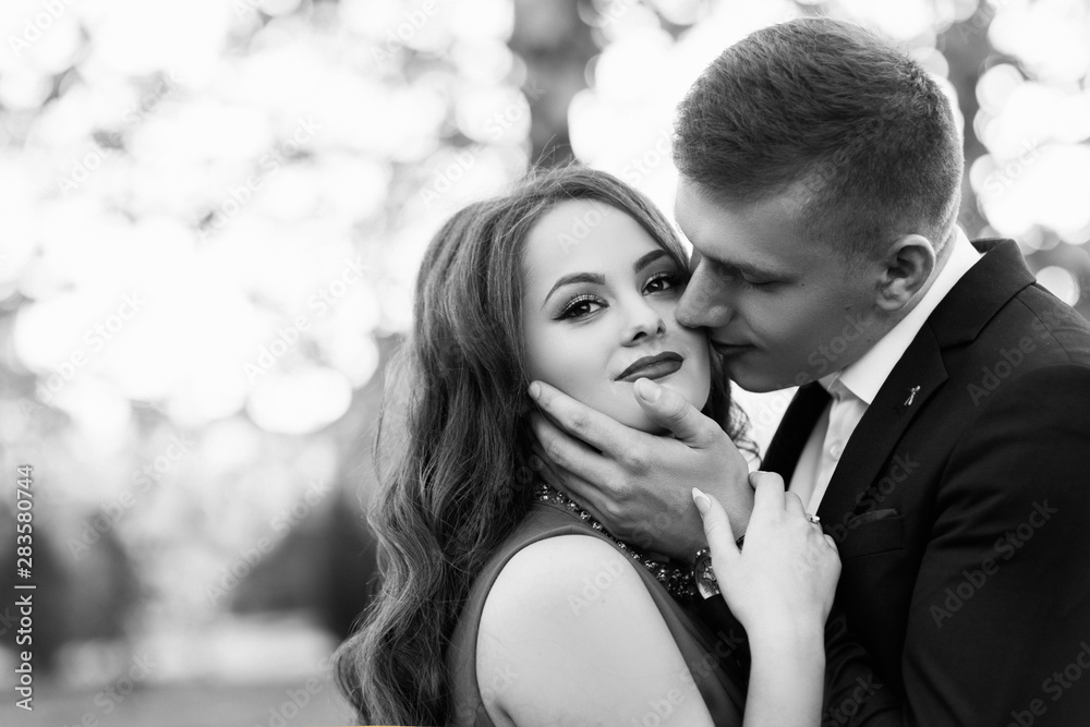 Naklejka premium Couple in love in autumn park, enjoying a beautiful autumn day. Man kissing a woman in a forehead. True love among lovers. Sincere emotions and love on the planet. Black and white