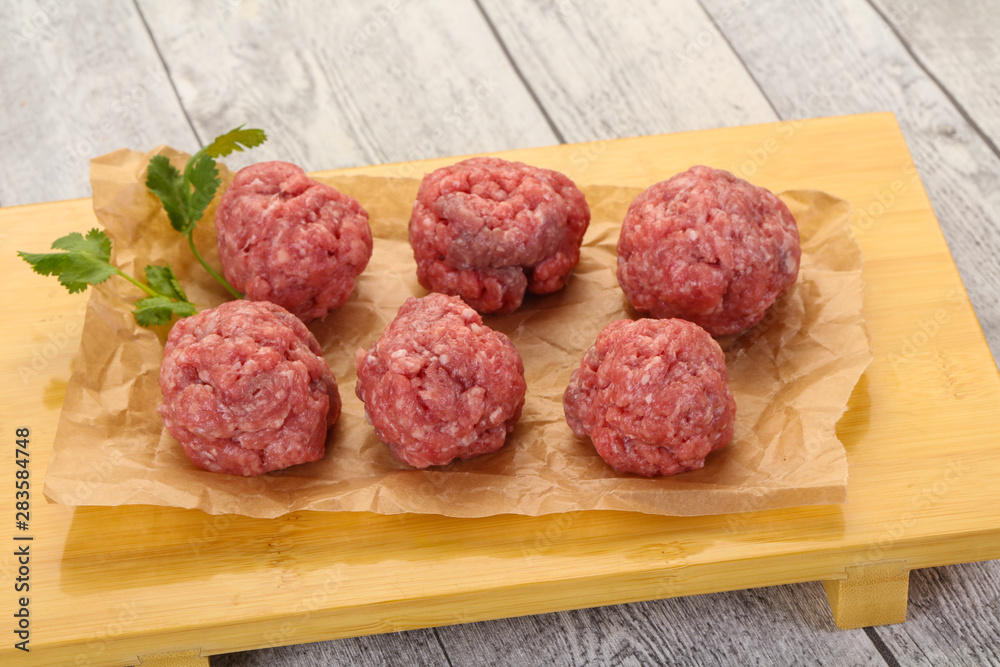 Raw meatball over wooden background Raw meatball over wooden background