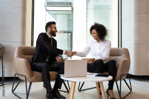 Smiling diverse business partners shaking hands at meeting